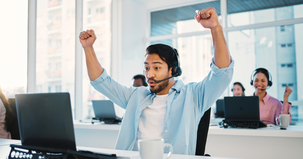 Sales agent cheering with his hands up after successfully making a cold call.