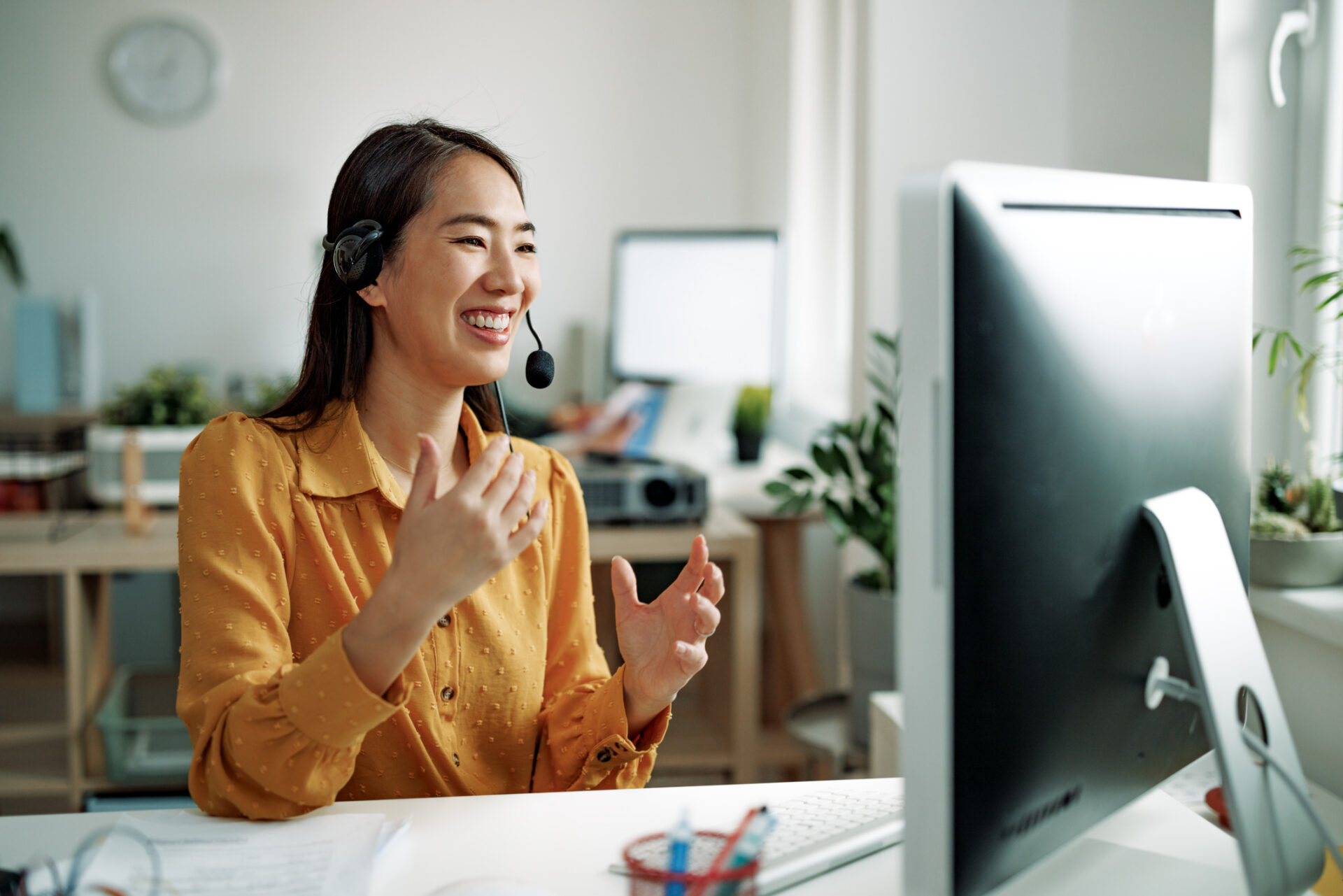 Outbound saleswoman wearing a headset and looking at her computer screen while on a sales call.