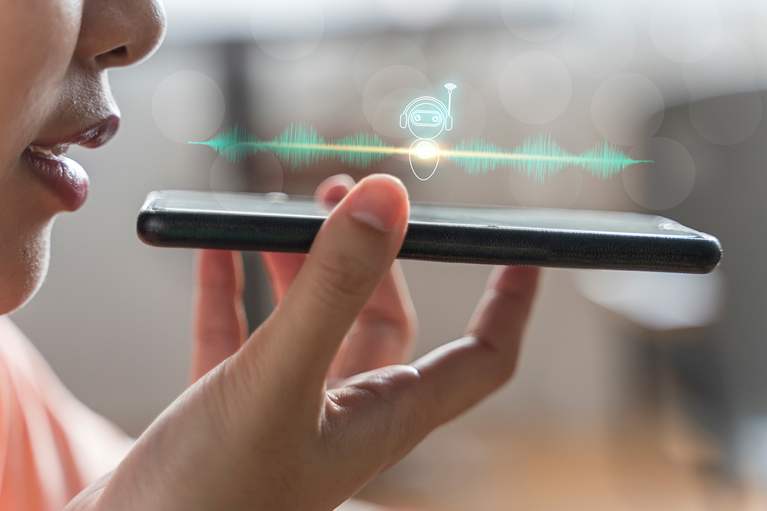 Person speaking into an iPhone with a digital voice assistant icon and sound wave graphics, representing AI technology like call screening in Apple iOS 26.