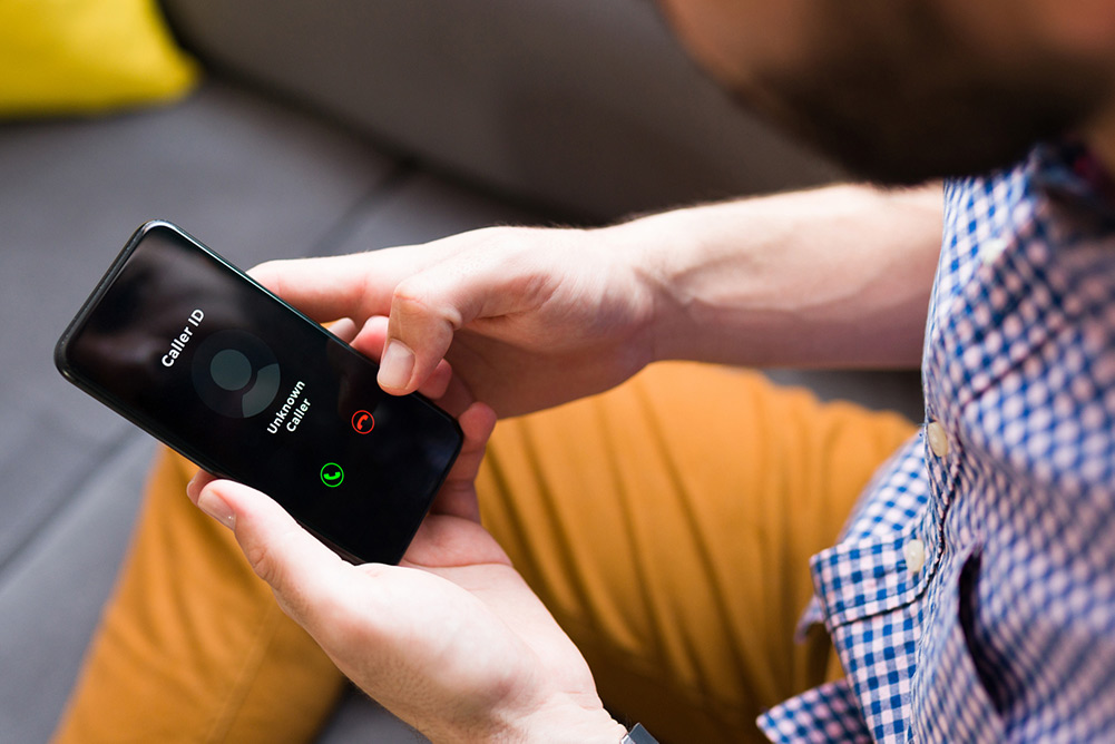 Man looking at his phone displaying an incoming call labeled “Unknown Caller,” illustrating an example of call labeling.