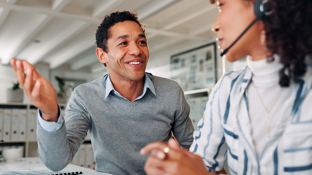 Sales agent talking to a lead generator about their lead generation process in an office setting.