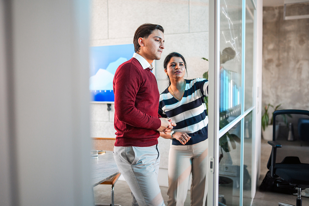Two business professionals reviewing performance charts on a screen, discussing potential strategies to scale outbound calling operations.